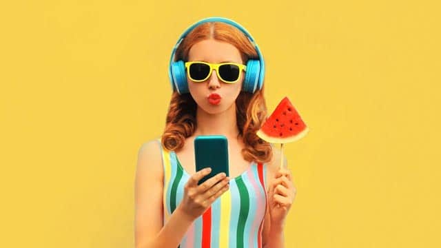 Frau hört Sommer Musik mit Handy und Kopfhörern